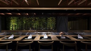 A restaurant with a long table set for a meal, surrounded by chairs.