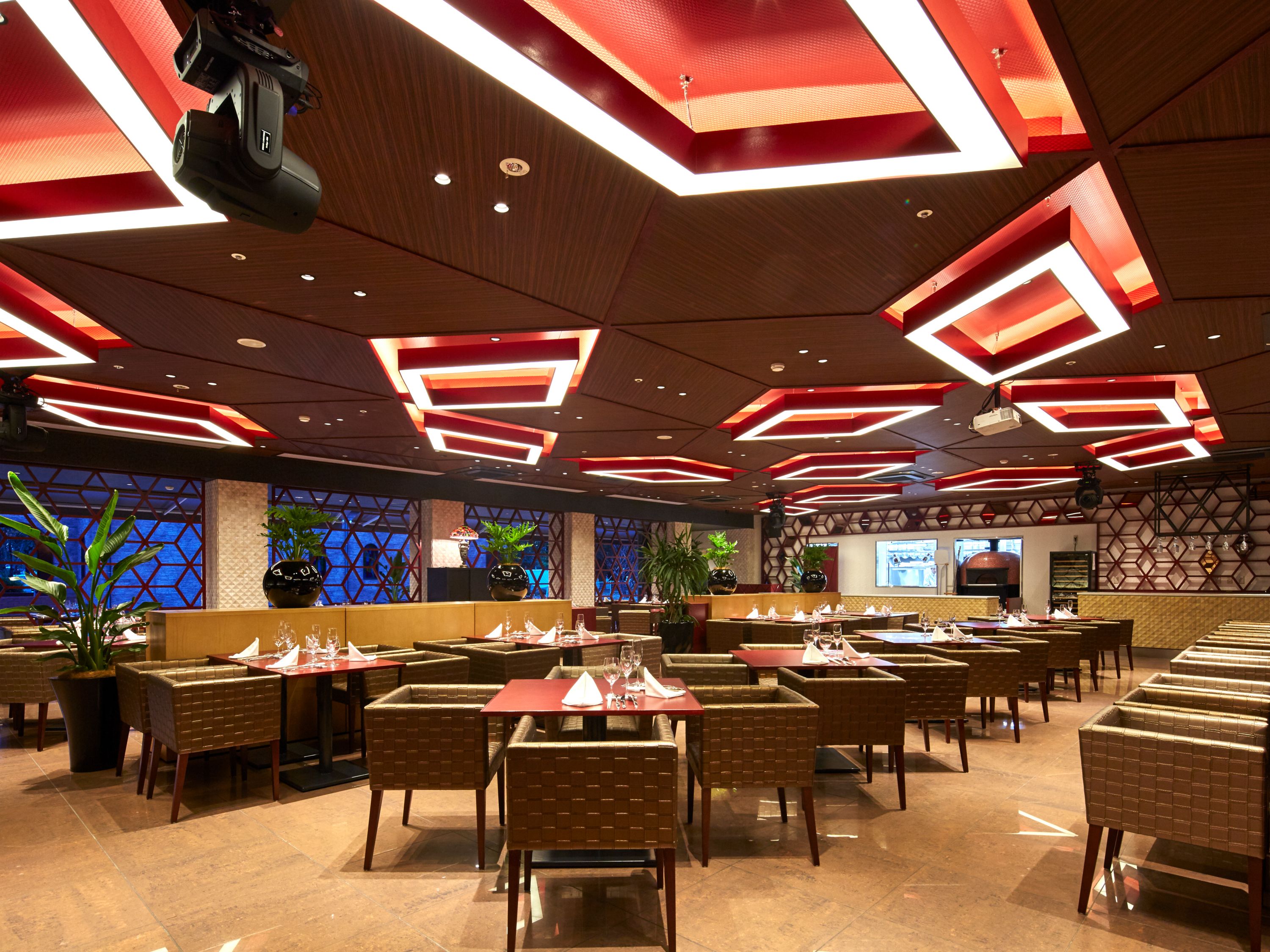 A spacious restaurant with high ceilings, modern lighting, and a variety of seating arrangements.