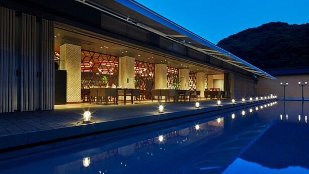 A modern hotel with a poolside bar and dining area, featuring a geometric facade and a clear view of the pool.