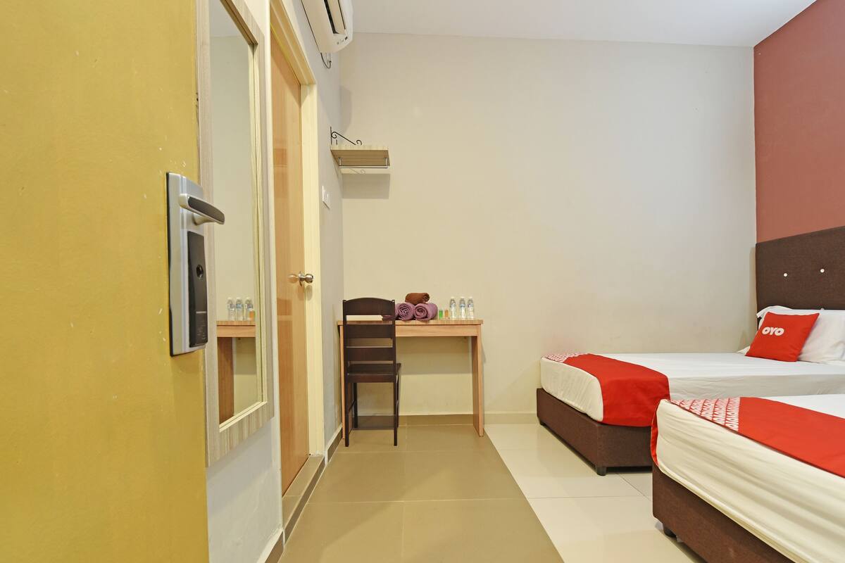 Une chambre d’hôtel équipée d’un lit, d’un bureau, d’une chaise et d’une petite table avec des articles de toilette.