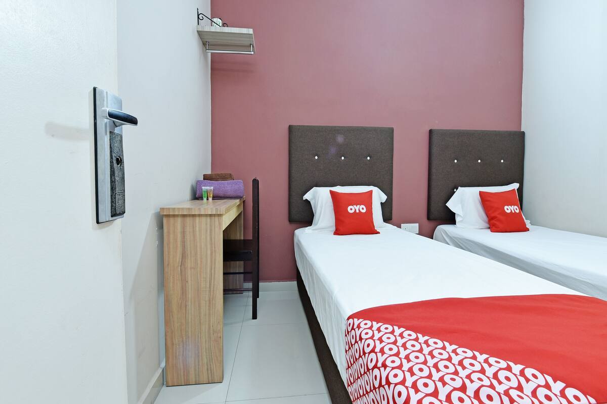 Une chambre d’hôtel avec deux lits, un bureau et une chaise.