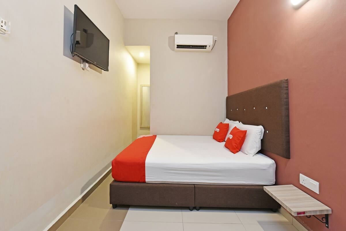 Une chambre à coucher comprenant un lit, un téléviseur fixé au mur, un appareil de climatisation et une table de chevet.
