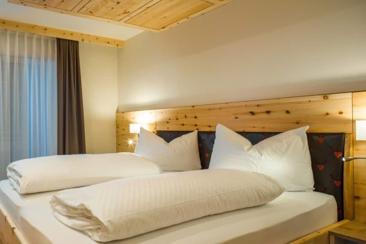 A hotel room with a wooden headboard, a desk, and a chair.