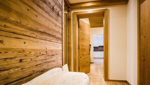 A narrow hallway with wooden walls and a wooden bench. - Luxapart Ambiente (Ladis)