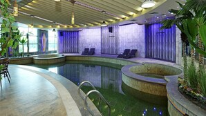 A modern indoor pool area with lounge chairs, a central pool, and a ceiling with patterned lighting.