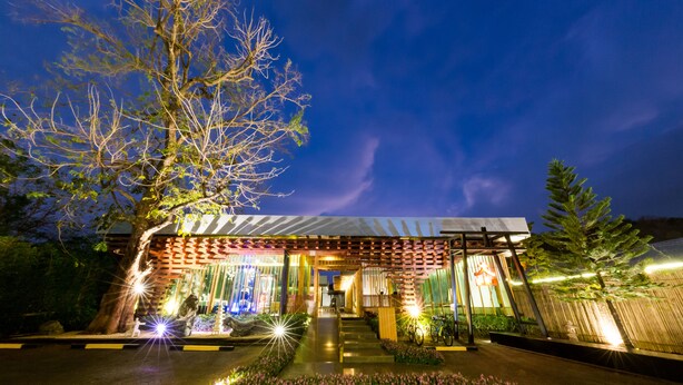 A modern building with a covered entrance, a staircase leading to the main area, and a large tree to the left. - Zen Villa Khao Yai (Pak Chong)