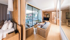 A modern, well-lit room with a wooden bed, a sofa, and a dining area. - Zen Villa Khao Yai (Pak Chong)