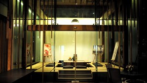 A modern room with a glass partition, a desk, a chair, and an easel with a painting. - Zen Villa Khao Yai (Pak Chong)