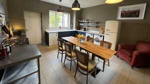 A compact kitchen with a dining area, a refrigerator, and a stove. - Ballylagan Organic Farm (Ballyclare)