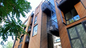 Ein modernes Gebäude mit einem einzigartigen architektonischen Design, das Backstein und Holz kombiniert, große Fenster aufweist und eine auffällige Feuerleiter besitzt.