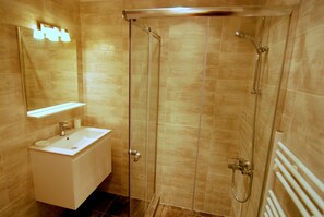 Ein modernes Badezimmer mit einer gläsernen Duschkabine, einem weißen Waschbecken und einem Spiegel darüber.