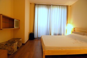Ein Hotelzimmer mit einem Bett, einem an der Wand befestigten Fernseher und Regalkisten an der Wand.
