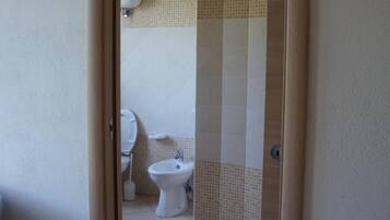 Ein Badezimmer mit Toilette, Bidet und gefliesten Wänden.