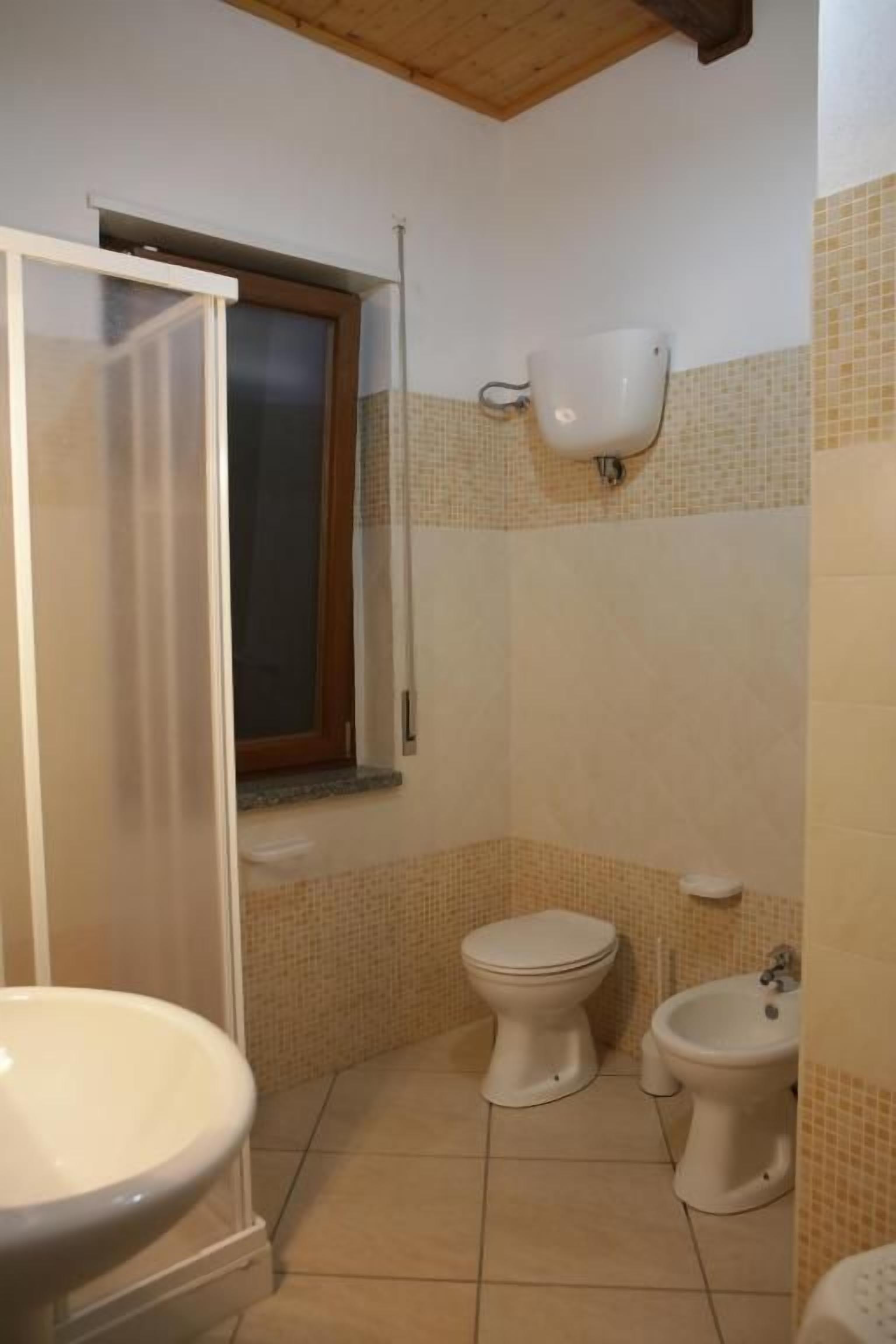 A bathroom with two toilets, a bidet, and a shower.