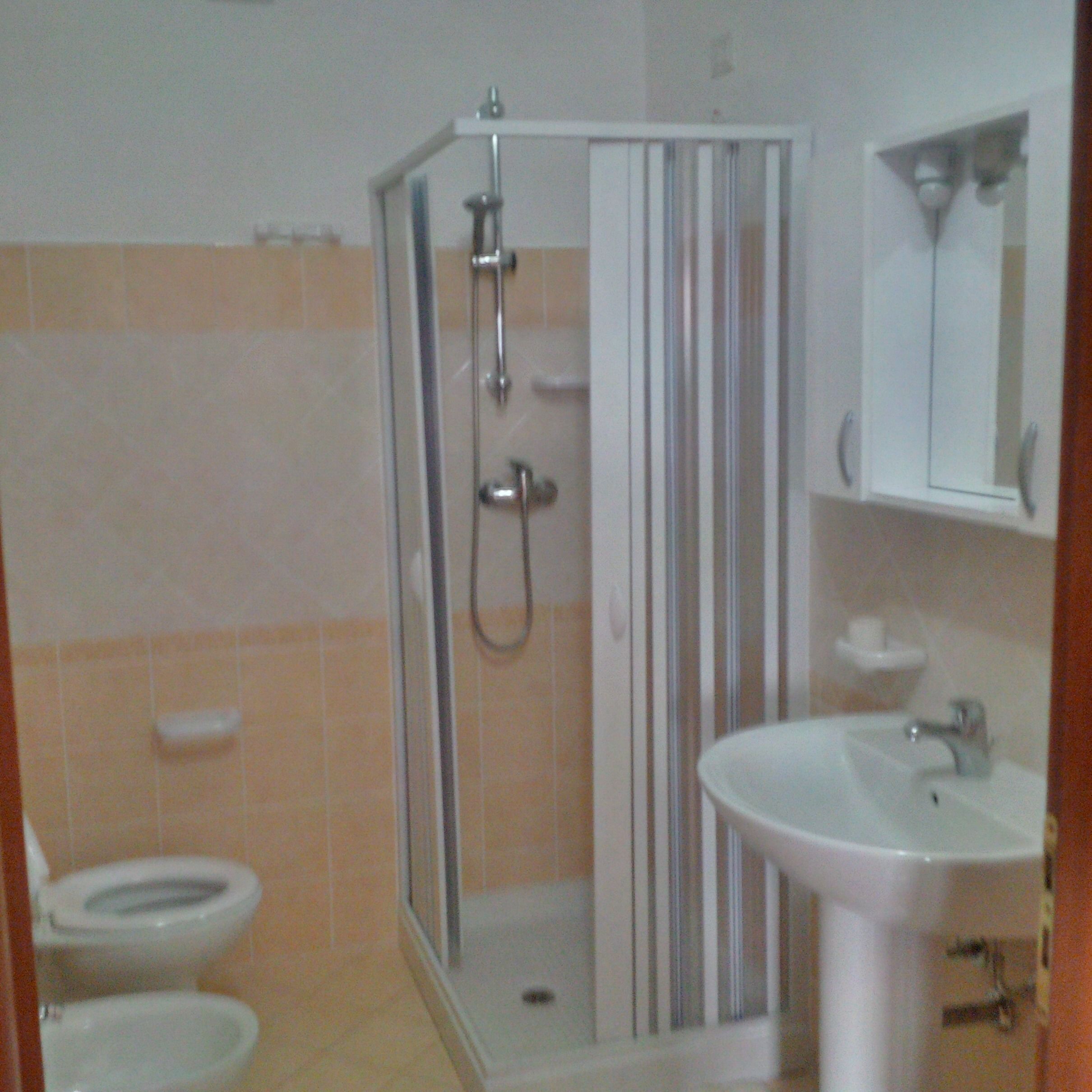 Une salle de bain comprenant un espace douche, des toilettes et un lavabo.