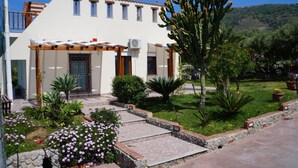Un bâtiment à deux étages, doté d’une façade blanche, de nombreuses fenêtres et d’un patio couvert.