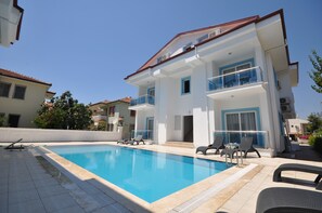 Alberca al aire libre, sombrillas en la alberca y camastros