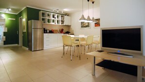 Cozinha moderna com geladeira, mesa de jantar, cadeiras e TV de tela plana.