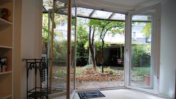 Quarto com porta de vidro que dá para um jardim, um suporte de metal e um tapete de boas-vindas.