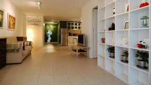 Uma sala de estar ampla, com sofá, televisão e estante de livros.