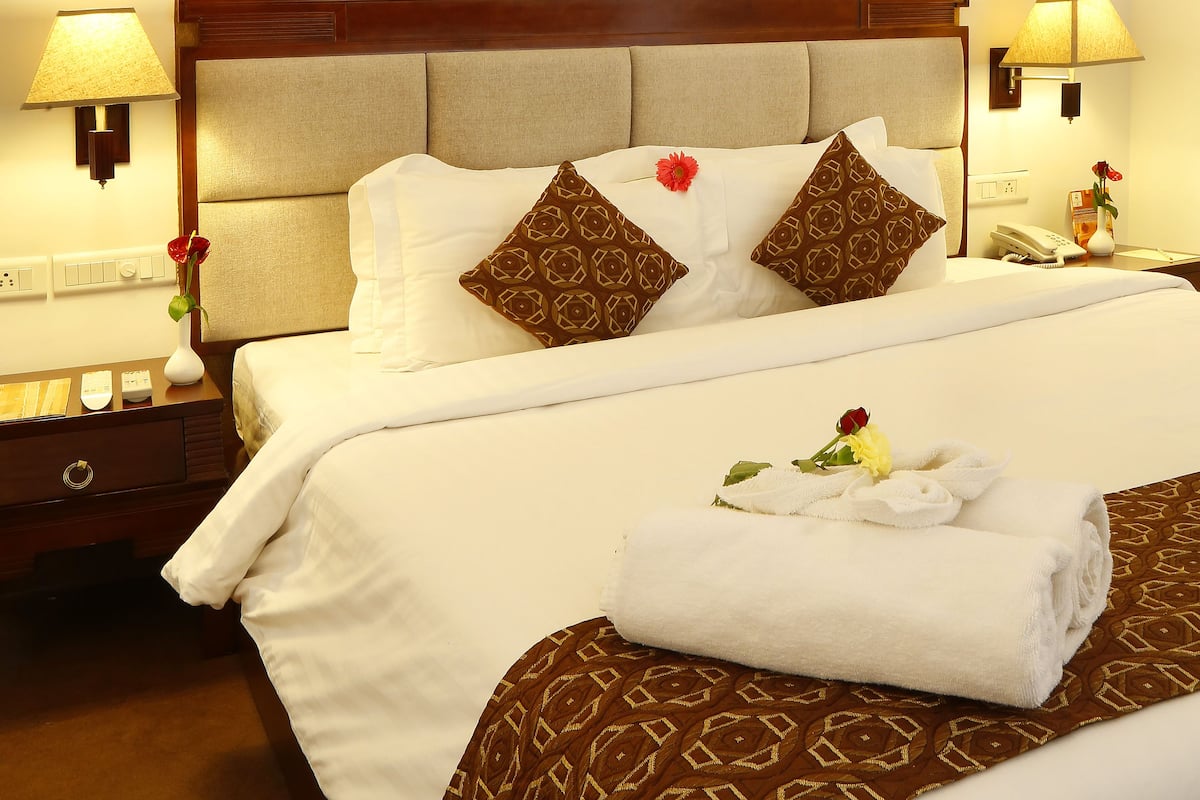 A hotel room with a large bed, a painting on the wall, and two bedside lamps.
