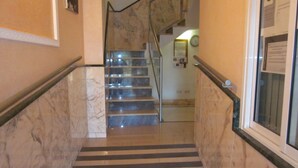 Un escalier en marbre, dont les contremarches sont rayées de noir et de blanc, mène à un palier.