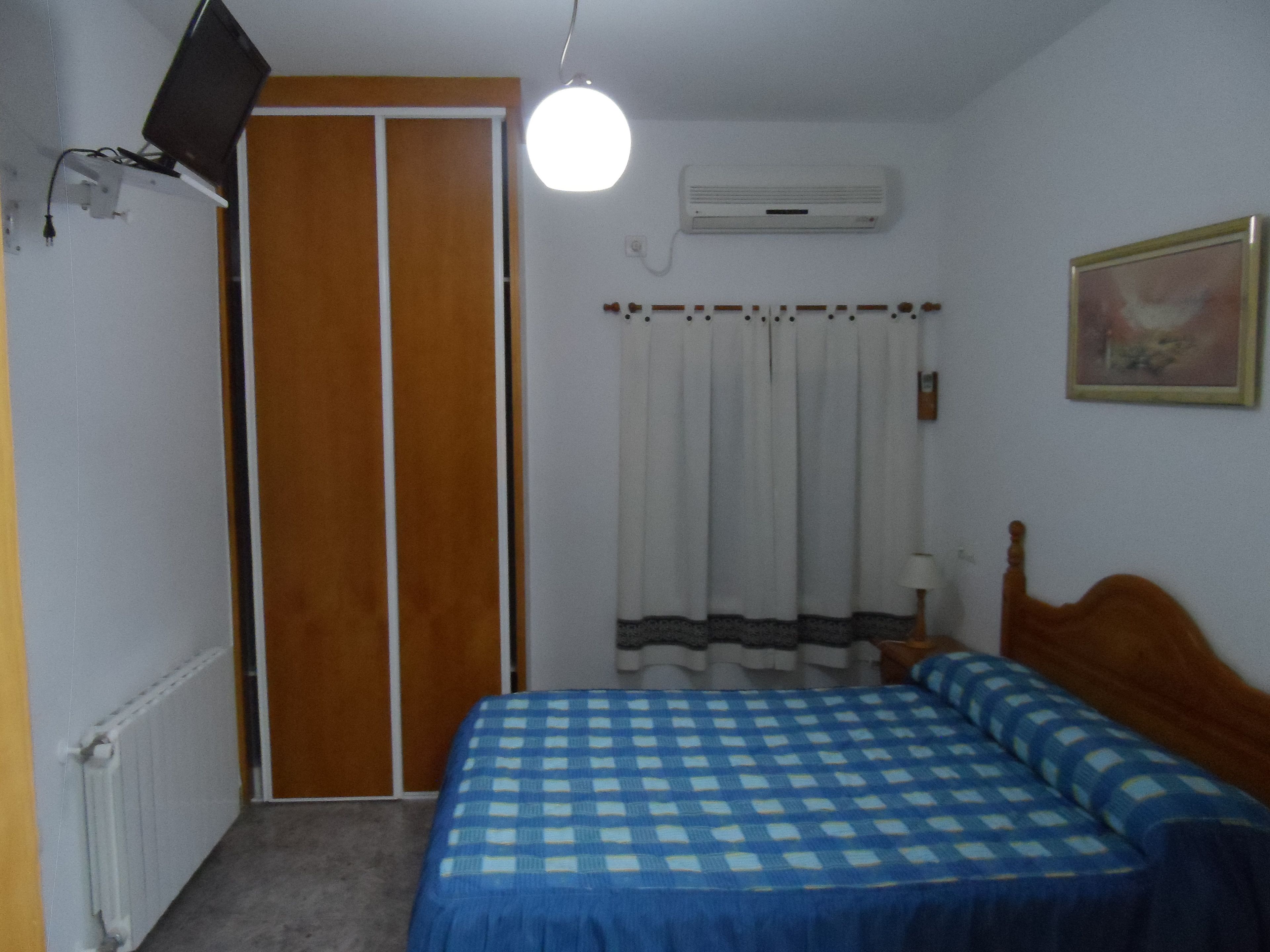 Une chambre à coucher avec un lit, une armoire, un climatiseur, un tableau et une lampe.
