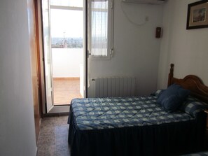Une chambre à coucher avec un lit, un radiateur, une porte donnant sur un balcon et un tableau encadré au mur.