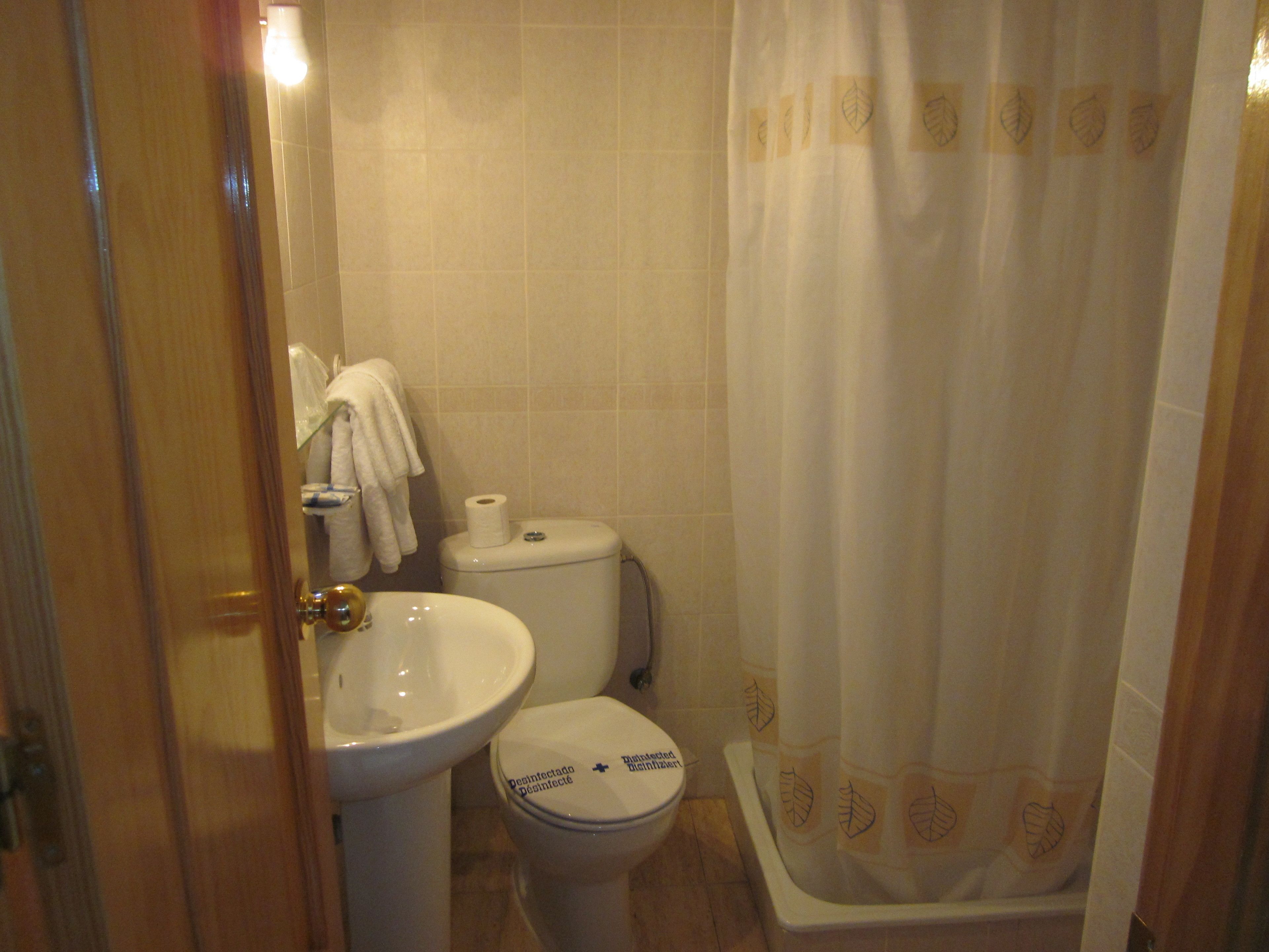 Un baño con inodoro, lavamanos y cortina de ducha.