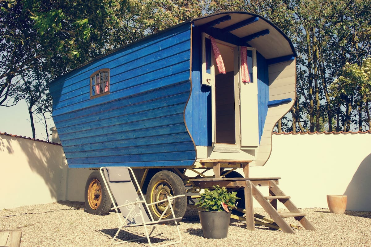 Una casa móvil azul con un pequeño porche y una maceta.