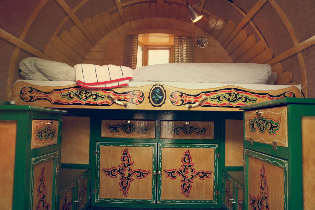 Una habitación de madera con una cama, armarios verdes y techo inclinado.