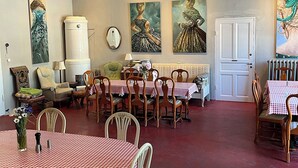 Un comedor con mesas y sillas a cuadros rojo y blanco, una puerta blanca y cuadros en las paredes.