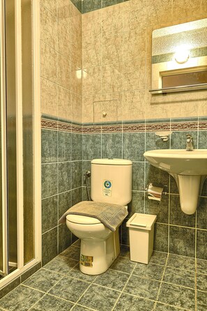 A bathroom with a toilet, sink, and shower area. - Baratero City Corner II Apartment (Sofia)