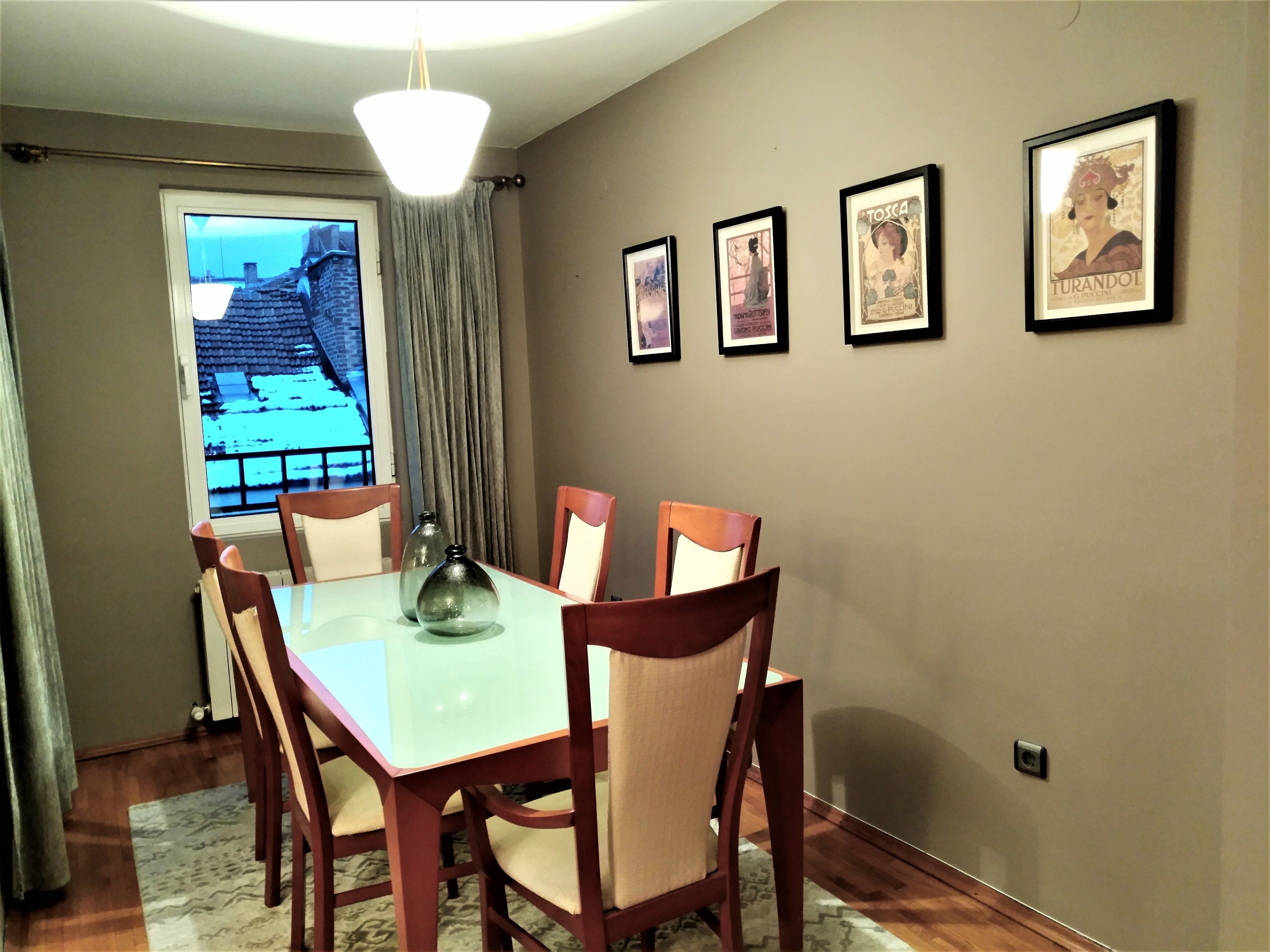 A dining area with a table and chairs, a chandelier, and framed pictures on the wall.