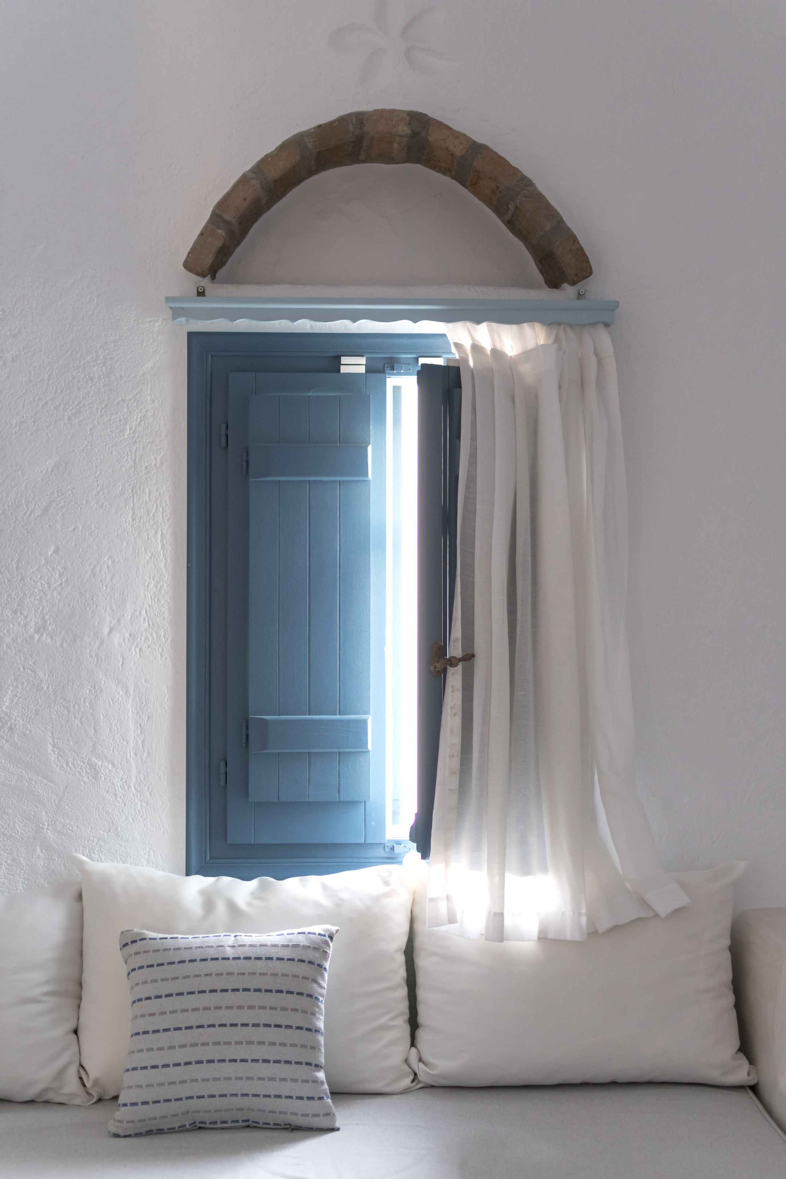 A room with a blue door, white curtains, and a white wall.