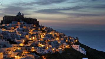 Un pueblo costero al anochecer, con edificios iluminados bajo un cielo crepuscular.
