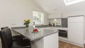 Une cuisine moderne dotée d’un îlot central, de meubles blancs et d’un four encastré.