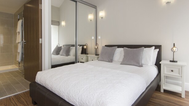 Une chambre à coucher moderne avec un grand lit, des tables de chevet et un dressing.