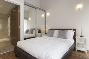 Un dormitorio moderno con una cama grande, mesitas de noche y un vestidor.