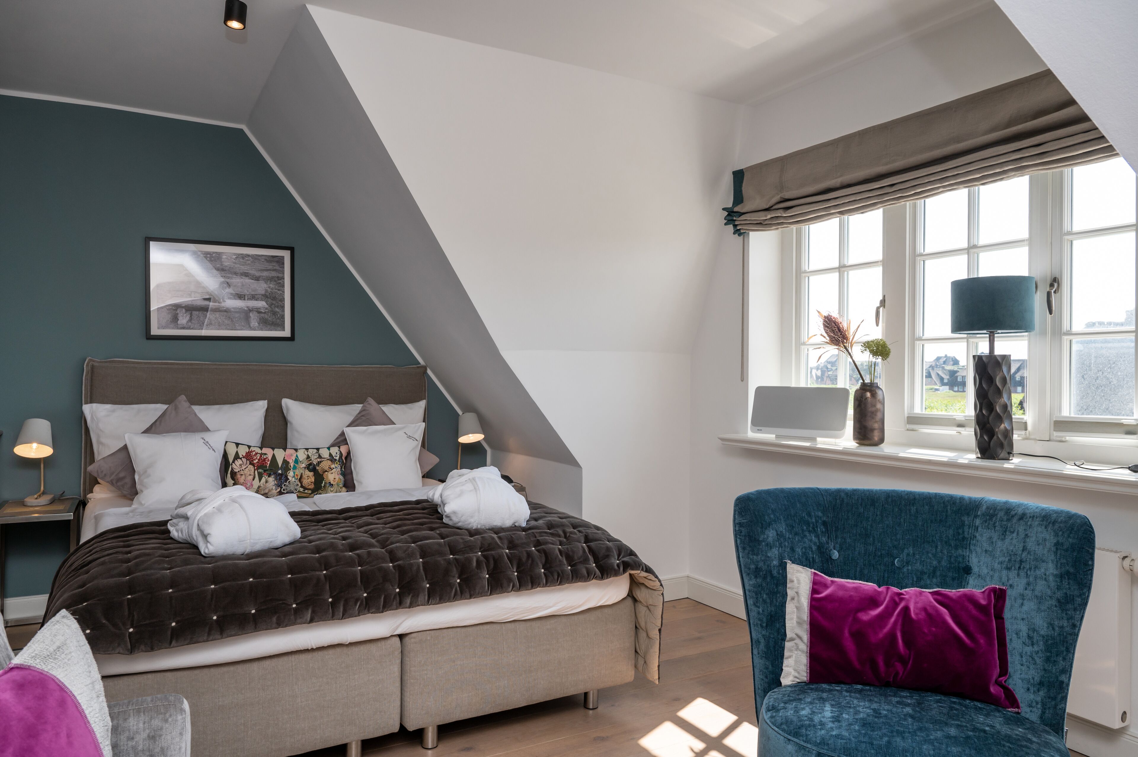 A modern bedroom with a large bed, a window with curtains, a desk, and a chair.