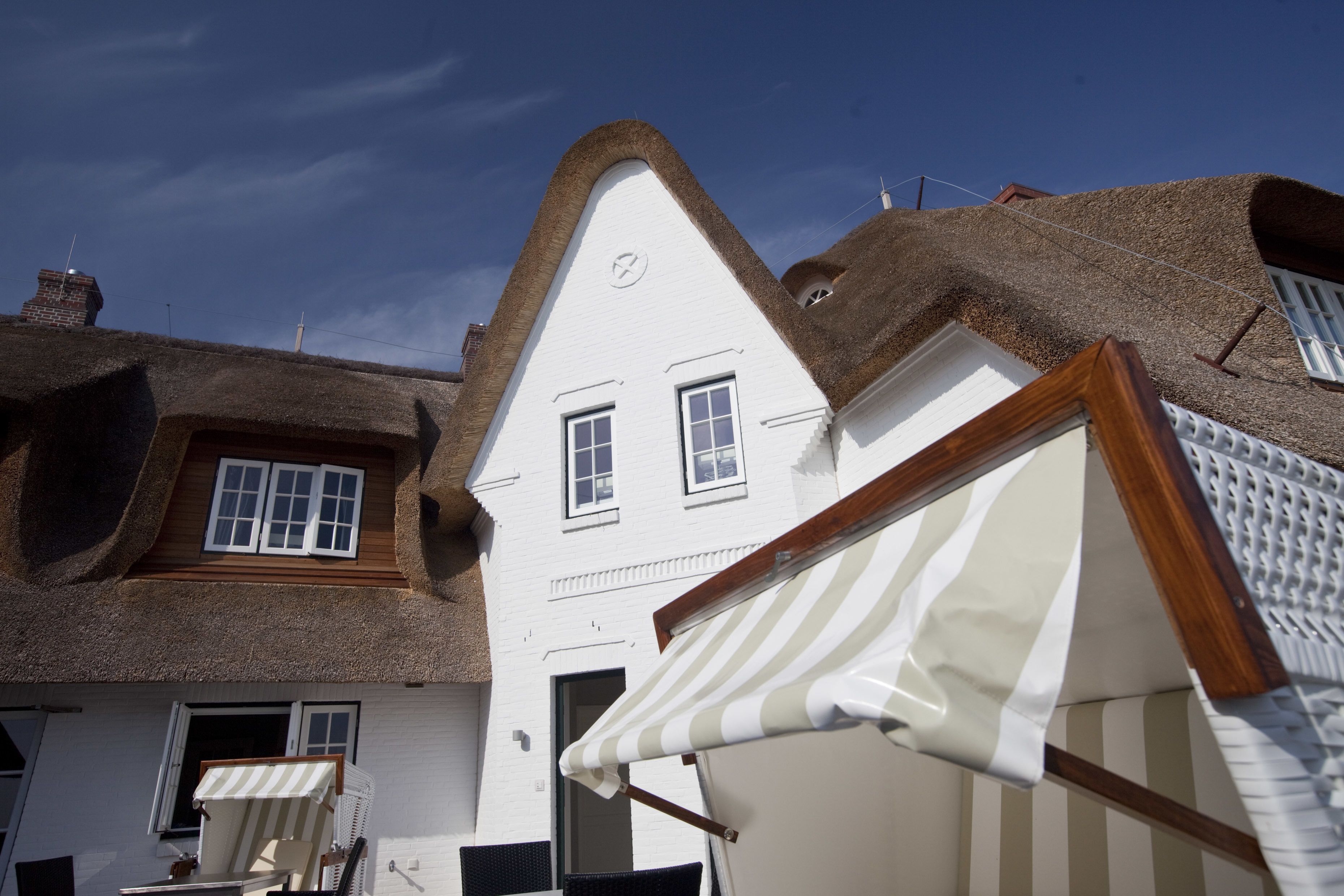 A traditional building with a steeply pitched roof and a white facade.