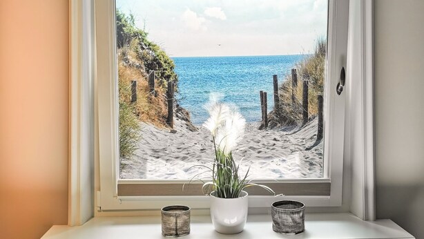 A window with a view of a sandy beach and the ocean. - Strandvogtei Sylt (Sylt)