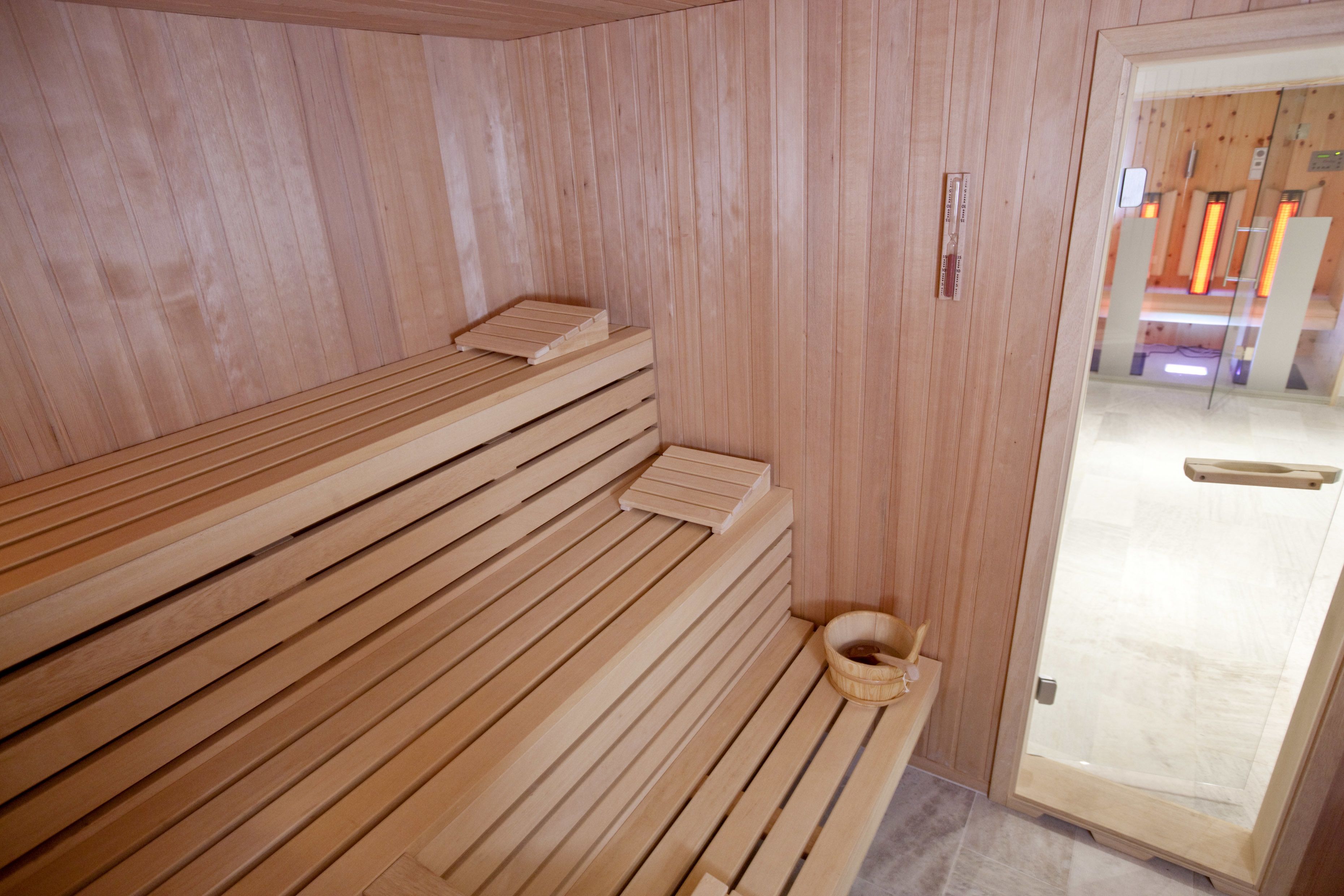 Una sauna de madera con bancos y un cubo de madera.