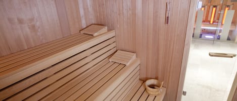En träbeklädd bastu med sittbänkar och en träspänd hink.