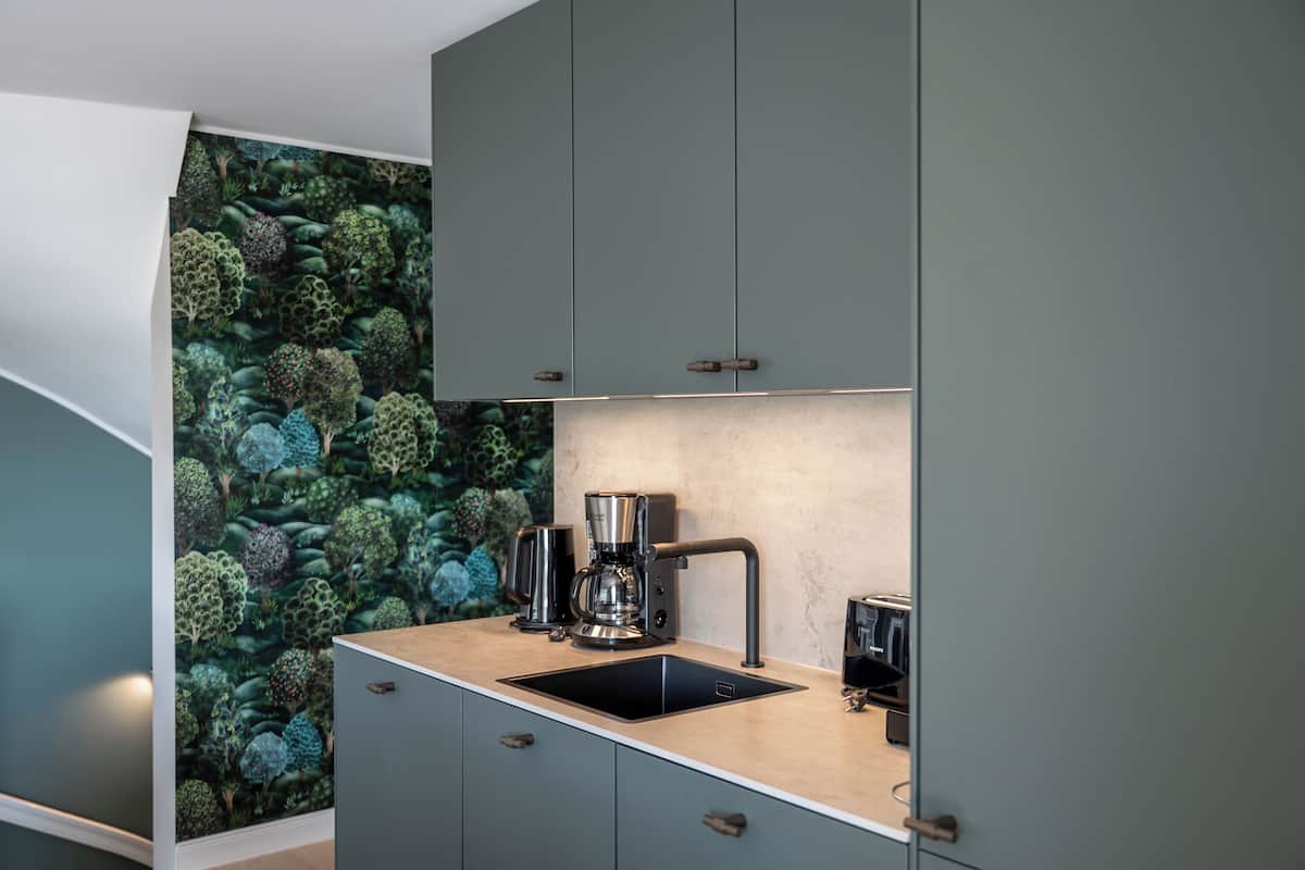 A compact kitchen with a modern design, featuring a built-in sink, a coffee maker, and a toaster.