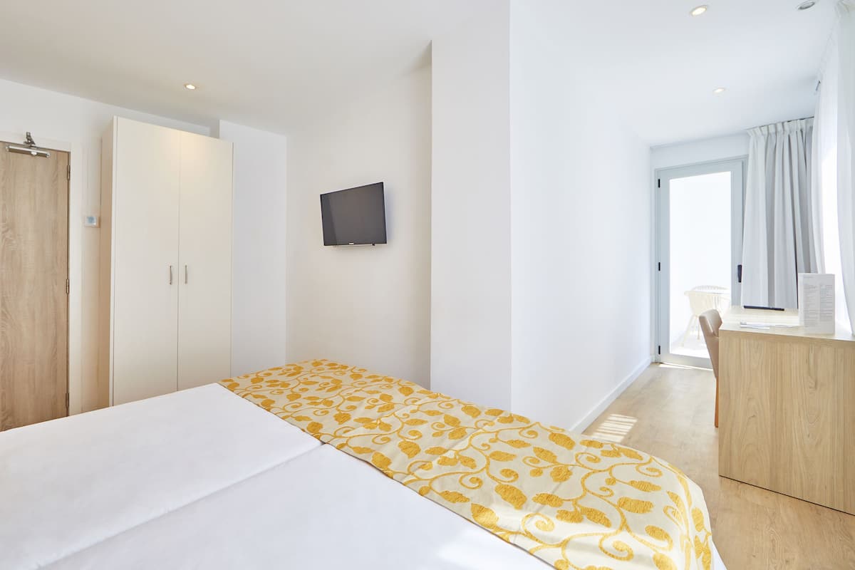 A hotel room with a bed, a desk, a TV, and a wardrobe.