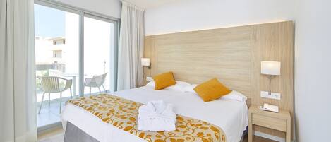 Habitación de hotel con una cama grande, dos lámparas de noche, un cabecero de madera y vistas al exterior.