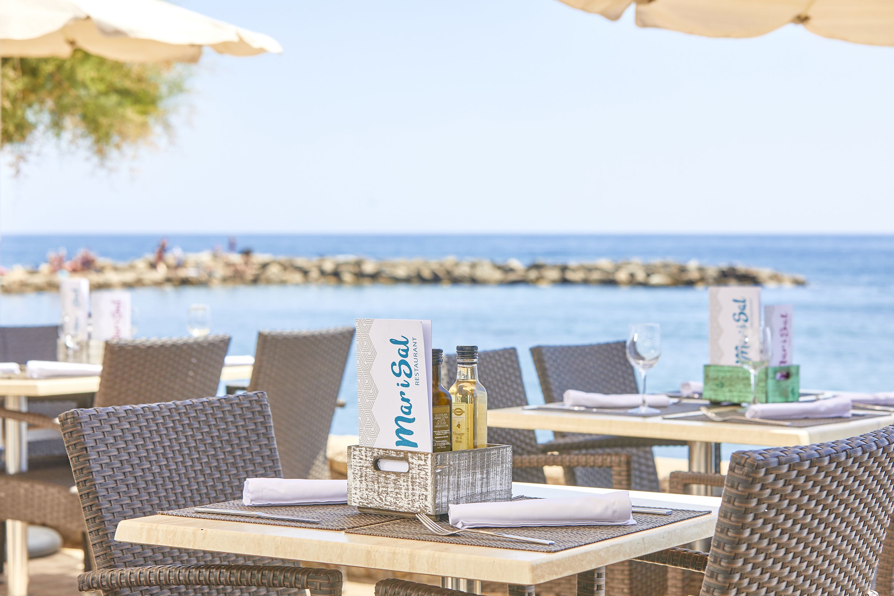 A seaside restaurant with wicker furniture and a sign reading "MariSal Restaurant".