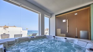 Un jacuzzi con vistas al mar, ventanas amplias y una puerta corredera.