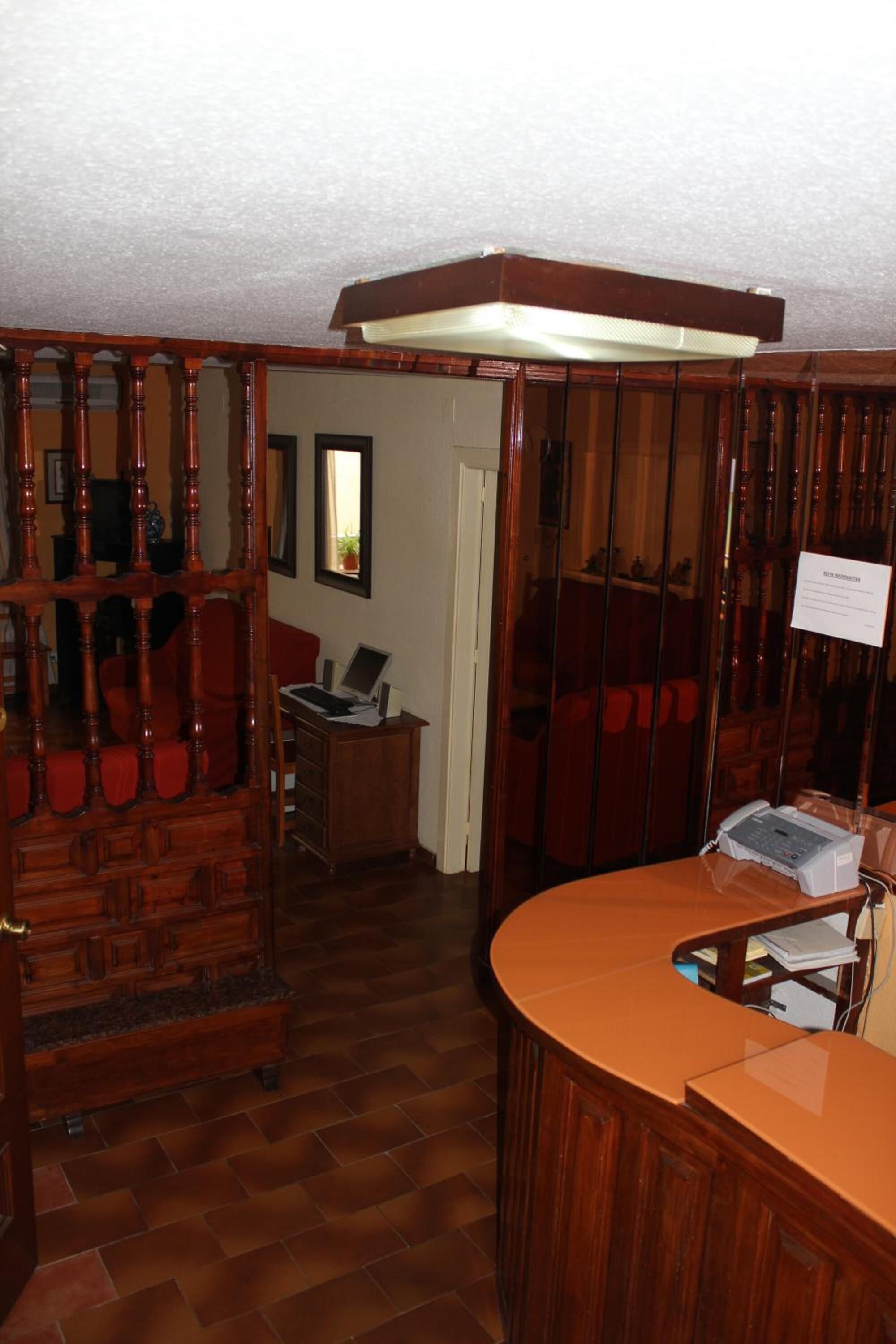 Una habitación con una cama con dosel de madera, un escritorio curvo de madera y una pequeña mesa con una computadora.